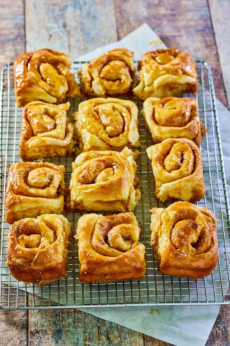 Top down view of cinnamon-filled carmel rolls on a cooling rack. - Hostess At Heart