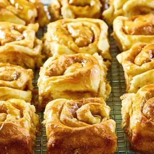 Angled view of soft gooey caramel rolls cooling on a baking rack. - Hostess At Heart