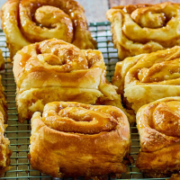 Baked Caramel Rolls Recipe sitting on a cooling rack - Hostess At Heart