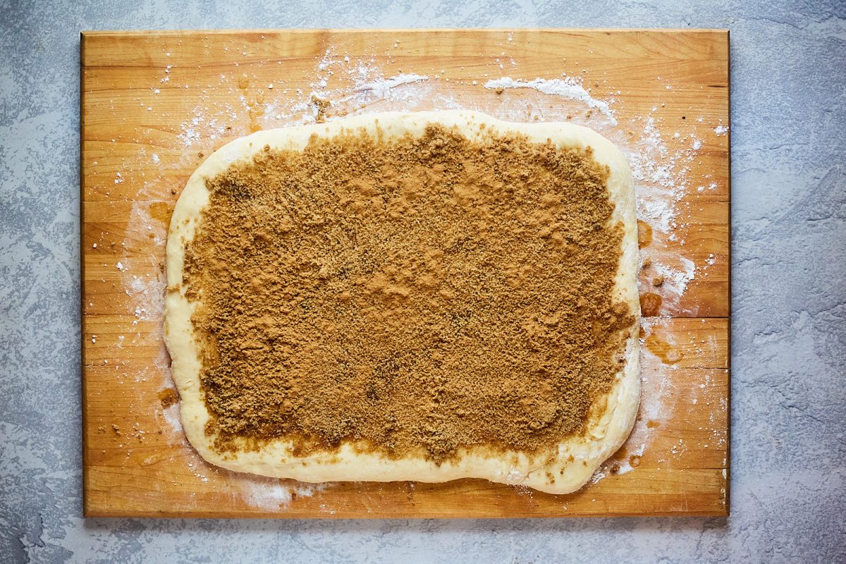 Top down view of rolled dough covered with cinnamon and brown sugar filling - Hostess At Heart