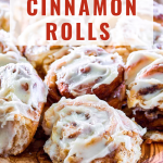Table view of homemade iced cinnamon rolls sitting on a cutting board - Hostess At Heart