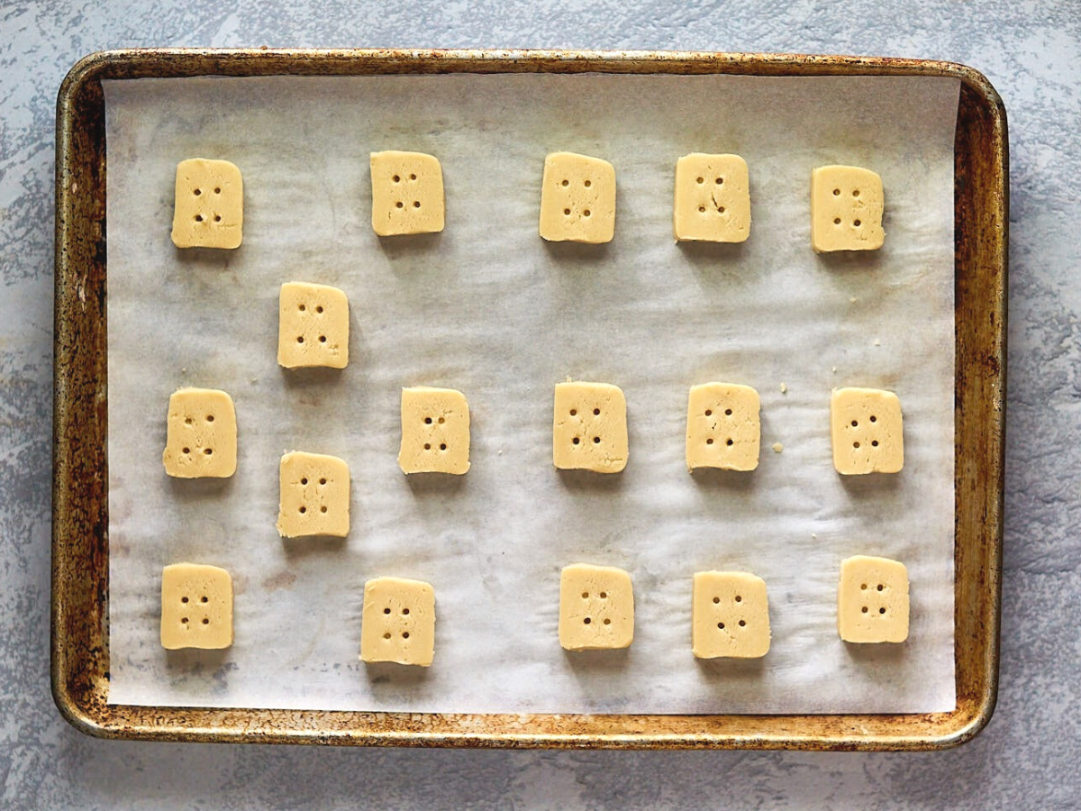 Cookies cut to resemble square buttons on a baking sheet. Hostess At Heart