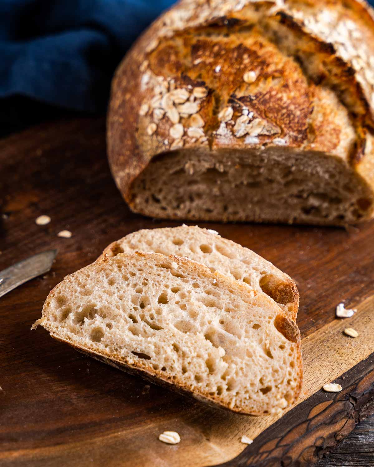 Two slices of sourdough rye carved from the loaf showing an airy crumb with a chewy crust.