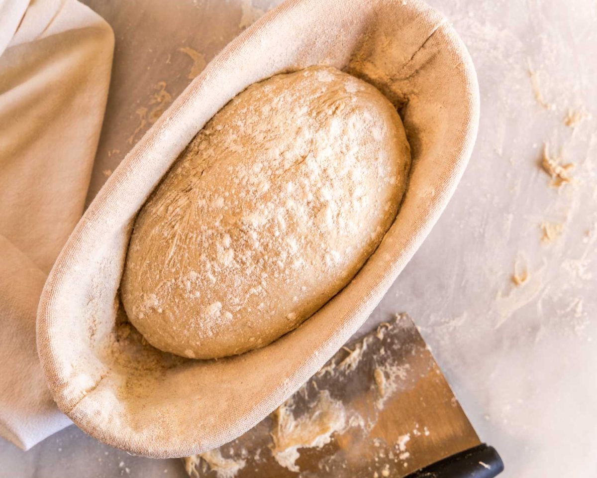 Bread dough dusted with flour sitting in a banneton basket - Hostess At Heart