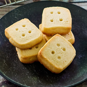 Top down view of little square cookies that look like dice on a plate - Hostess At Heart