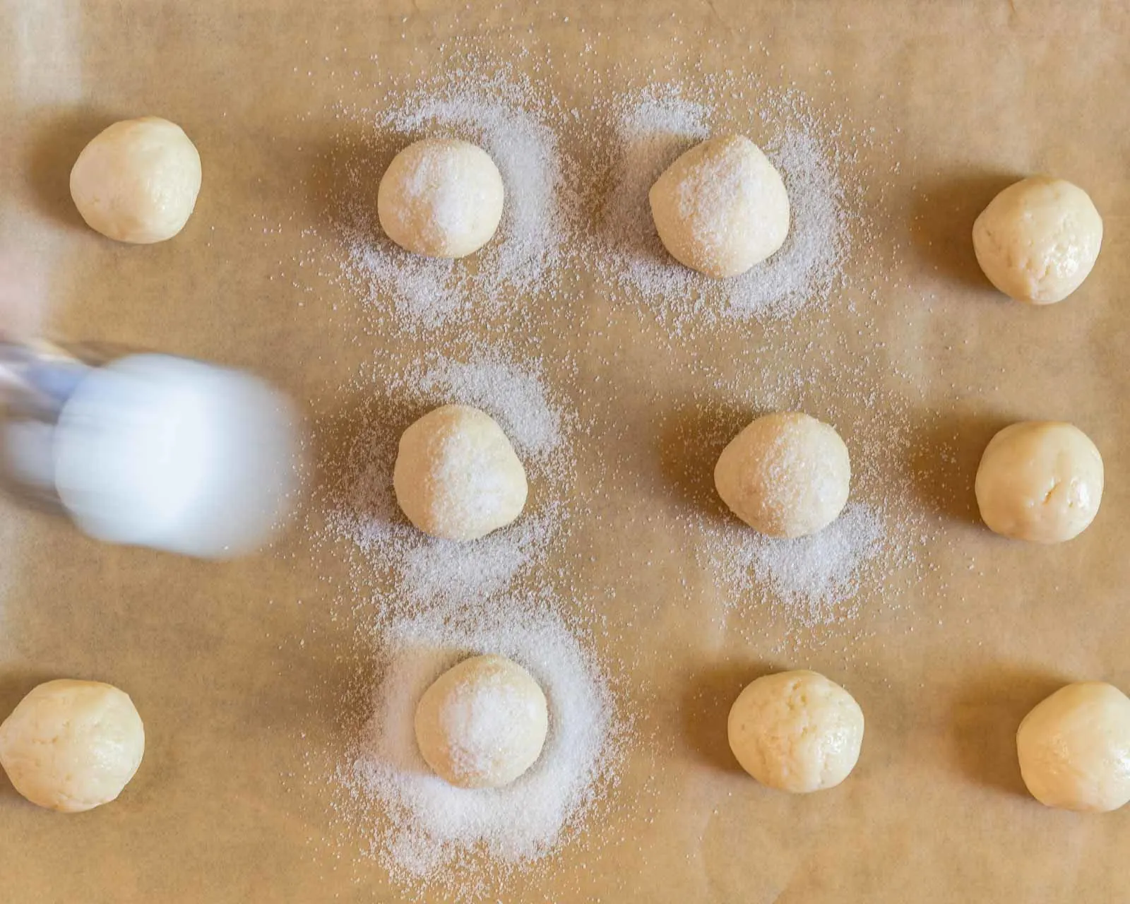 Top down view of sugar sprinkled over balls of sour cream sugar dough. - hostess at heart