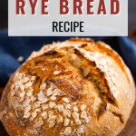 Front view of a loaf of bread topped with oats sitting on a cutting board. - Hostess At Heart