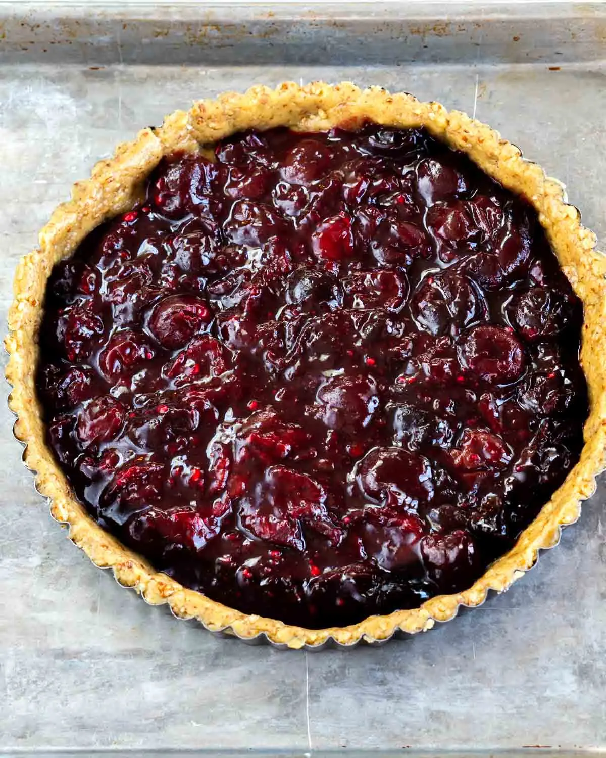 Top down view of a cherry filled pecan tart shell sitting on a baking rack. Hostess At Heart