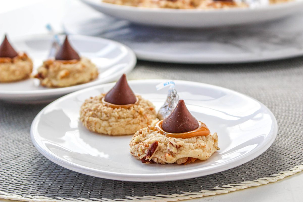 Two blossom cookies with caramel running from the center and topped with candy chocolate kisses. Hostess At Heart