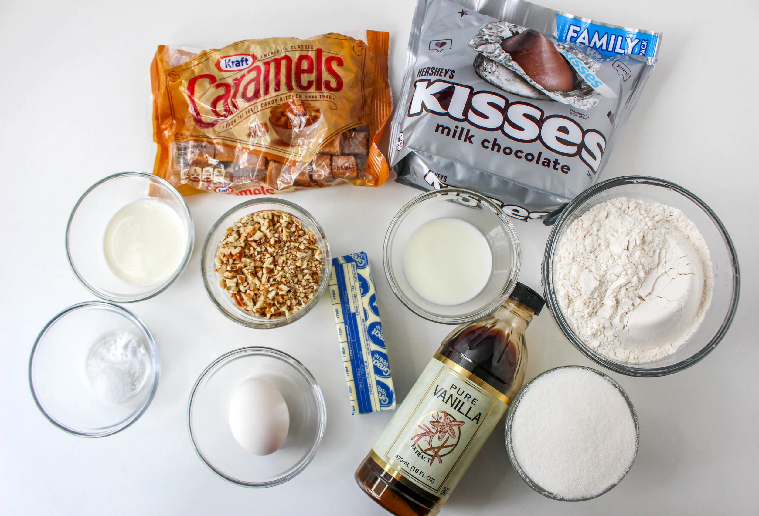 Ingredients used to make tutle thumbprint cookies including vanilla, sugar, egg, butter, flour, buts, caramel, chocolate kisses, baking soda and cream. Hostess At Heart