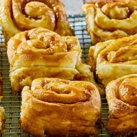 Side view of soft and tender baked caramel rolls sitting on a cooling rack - Hostess At Heart