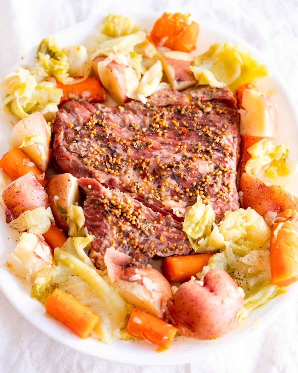 Angled view of a tender Instant pot corn beef brisket surrounded by cooked vegetables - Hostess At Heart