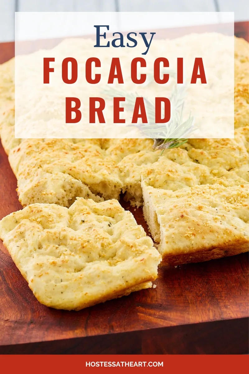 Angled view of sliced focacia bread topped with a sprig of rosemary and sitting on a wooden cutting board - Hostess At Heart