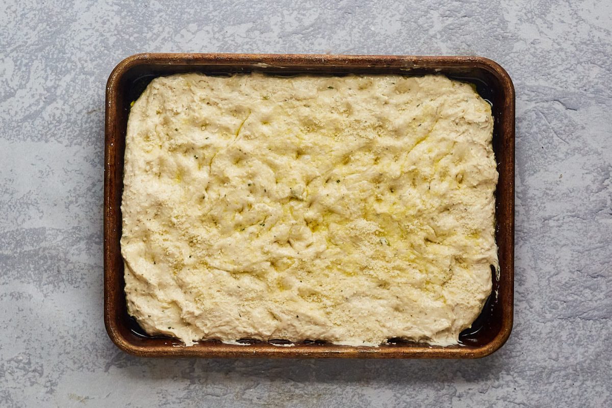 Top down view of focaccia dough shaped on a baking sheet. - Hostess At Heart