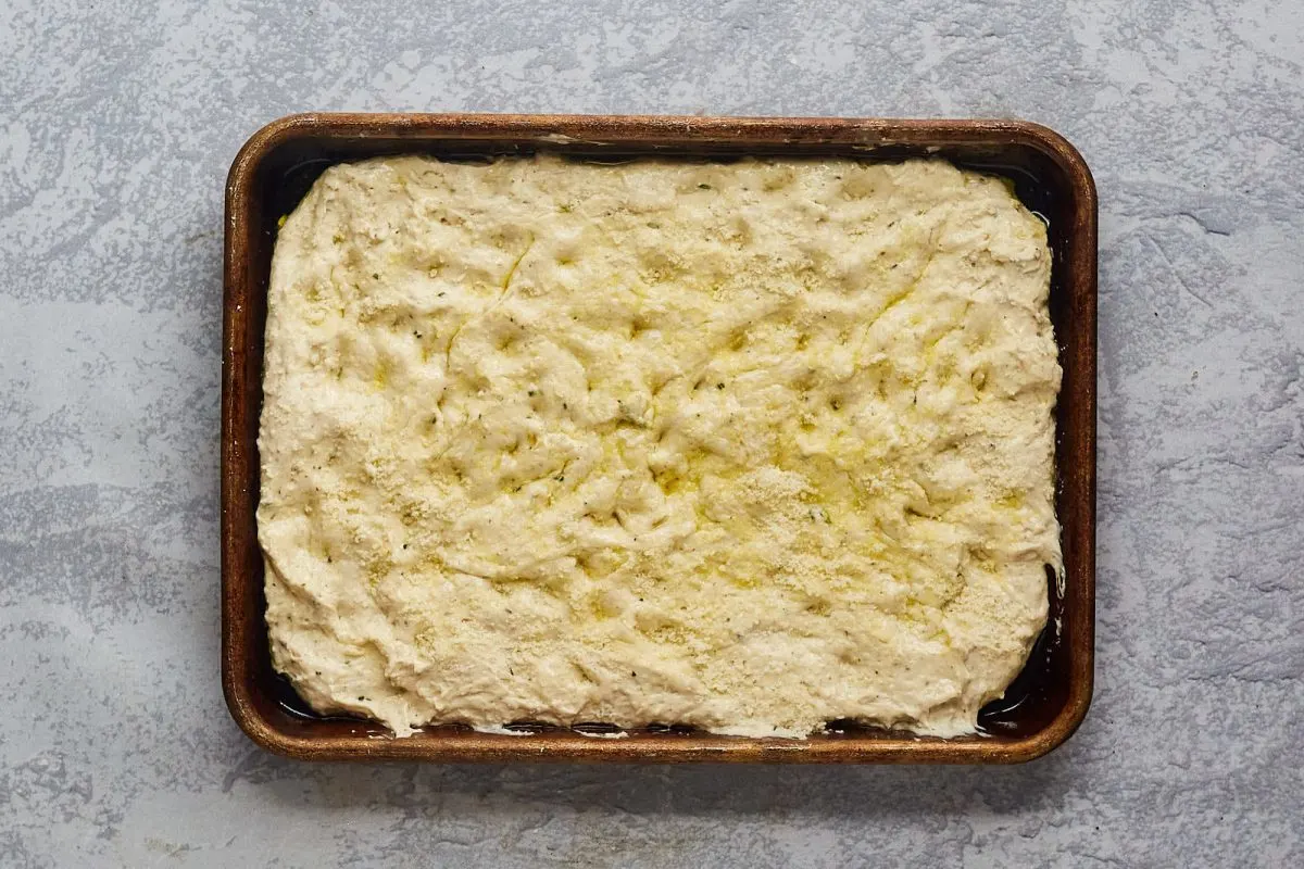 Top down view of focaccia dough shaped on a baking sheet. - Hostess At Heart