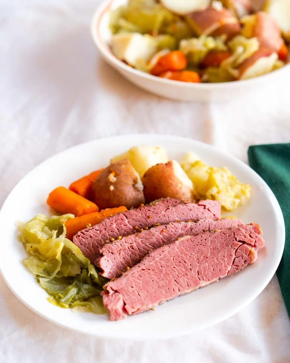 Angled view of a plate with sliced corn beef and vegetables - Hostess At Heart