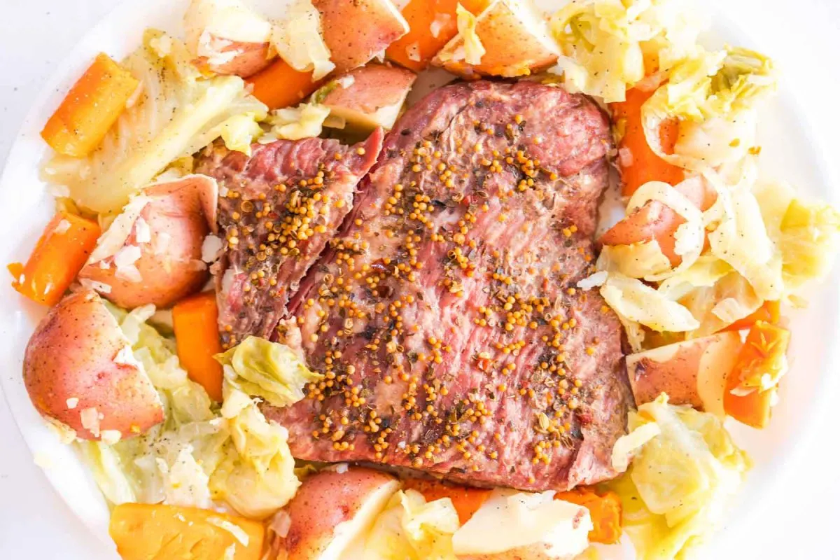 Top down view of a instant pot cooked corned beef brisket surrounded by cooked potatoes, cabbage, and carrots - Hostess At Heart