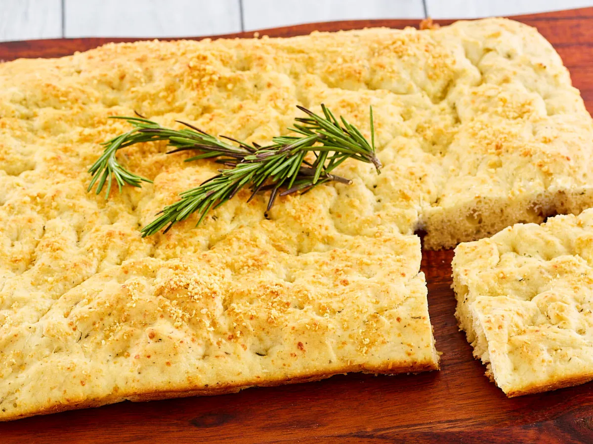 Side view of Italian Focaccia topped with a sprig of rosemary. Hostess At Heart