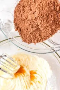 Sifted cocoa being added to creamed butter and sugar.