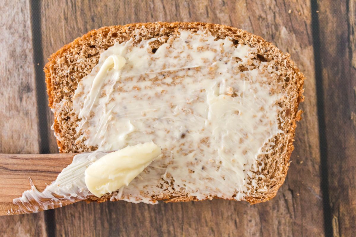 Top down view of a knife filled with butter on top of a slice of buttered bread