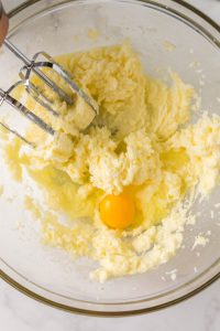 An egg added to creamed butter and sugar in a bowl - Hostess At Heart