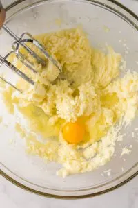 An egg added to creamed butter and sugar in a bowl - Hostess At Heart