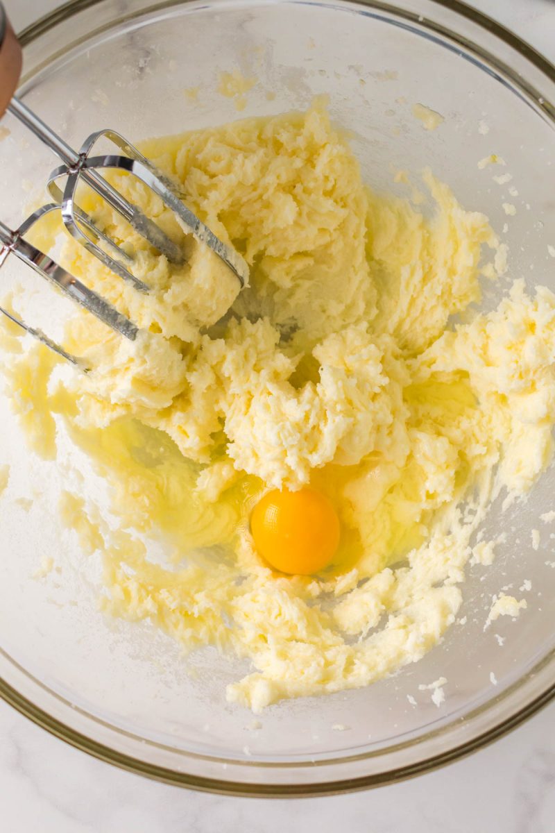 An egg added to creamed butter and sugar in a bowl - Hostess At Heart