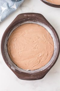 A round cake pan filled with chocolate cake batter - Hostess At Heart