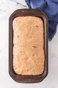 Top down view of a risen loaf of bread in a loaf pan. Hostess At Heart