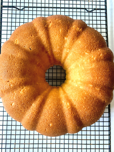 Top down view of a baked pound cake sitting on a cooling rack. Hostess At Heart
