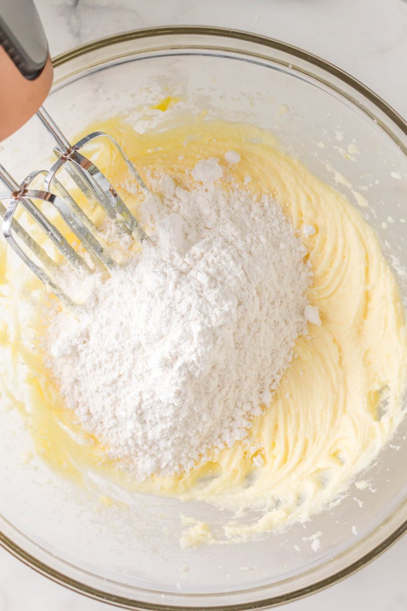 Dry cake ingredients added to creamed mix in a bowl - Hostess At Heart