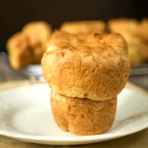 Sideview of a popover baked golden brown and sitting on a white plate. Hostess At Heart