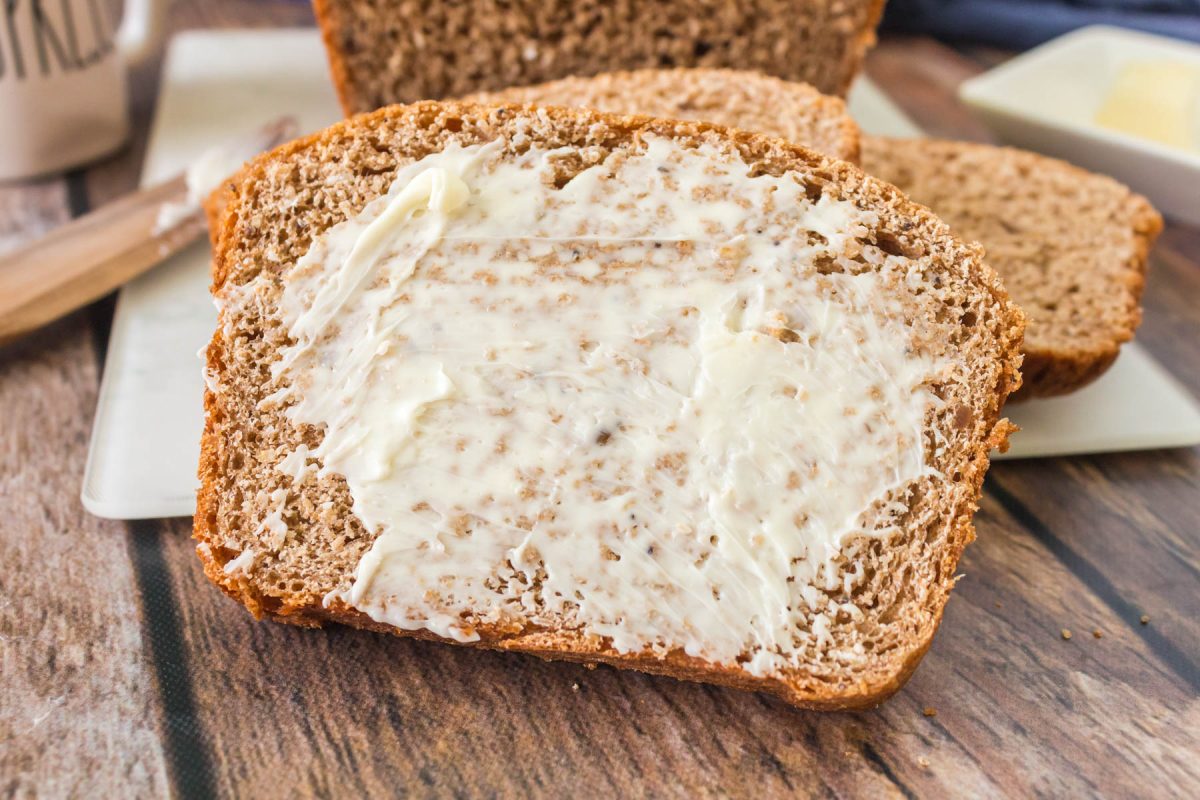 Tableview of a slice of Whole Grain Bread slathered in butter - Hostess At Heart