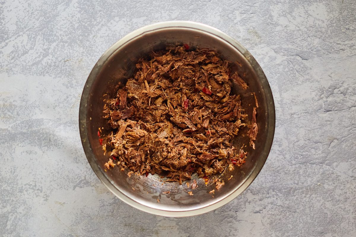 A bowl filled with shredded beef birria meat - Hostess At Heart
