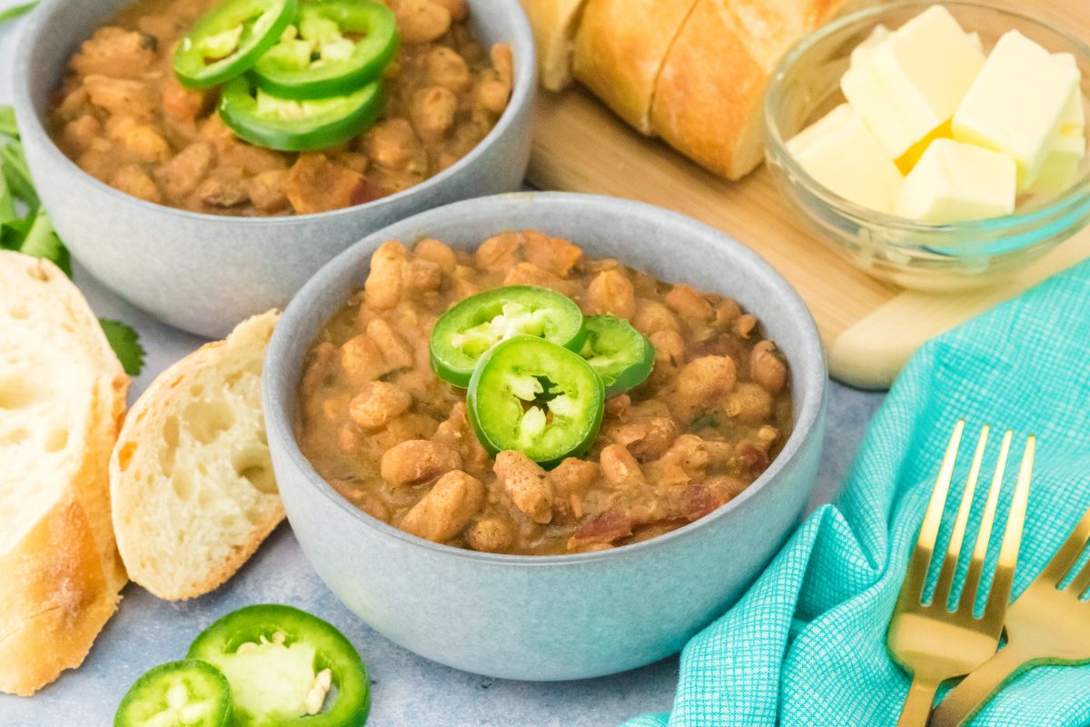 Angled view of bowls of cooked Charro Beans topped with slices of Jalapeno peppers