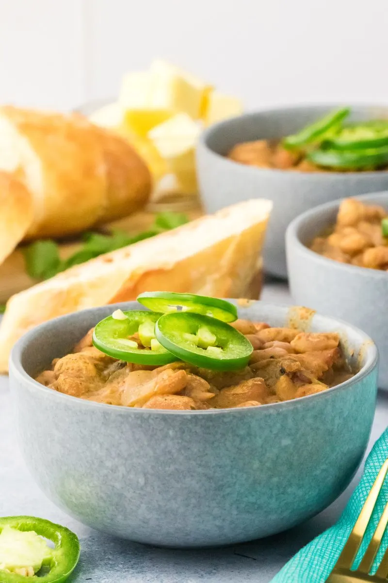 Side view of a bowl of cooked Mexican pinto beans topped with Jalapenos - Hostess At Heart