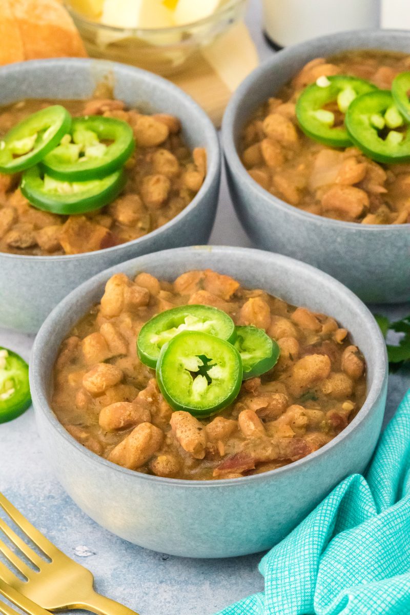 Angled view of a bowl of cooked Pinto beans topped with jalapeno pepper slices - Hostess At Heart