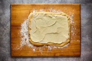 Dough rolled out in a rectangle topped with a cream cheese filling - Hostess At Heart