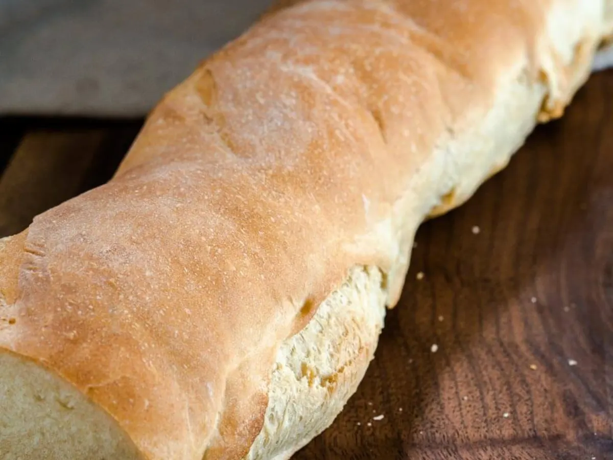 Angled view of a crusty loaf of bread sitting on a cutting board - Hostess At Heart