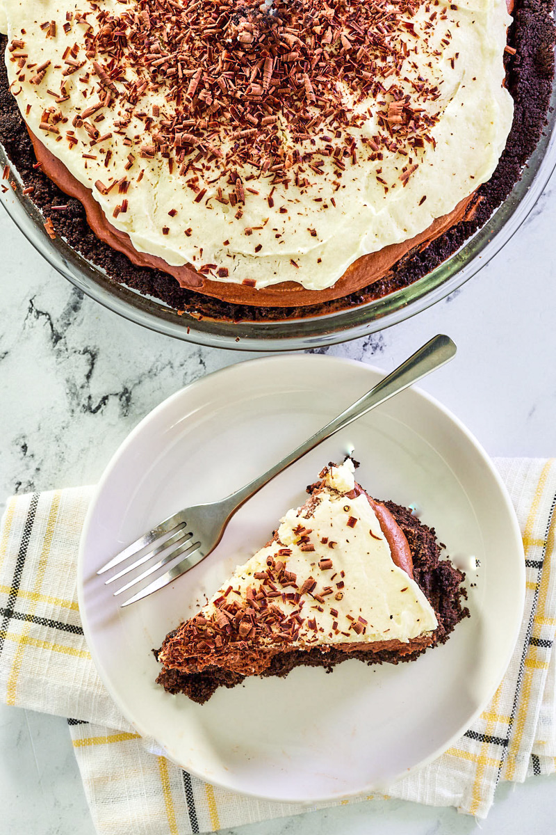 Top-down view of a slice of chocolate French Silk pie with the whole pie in the back - Hostess At Heart