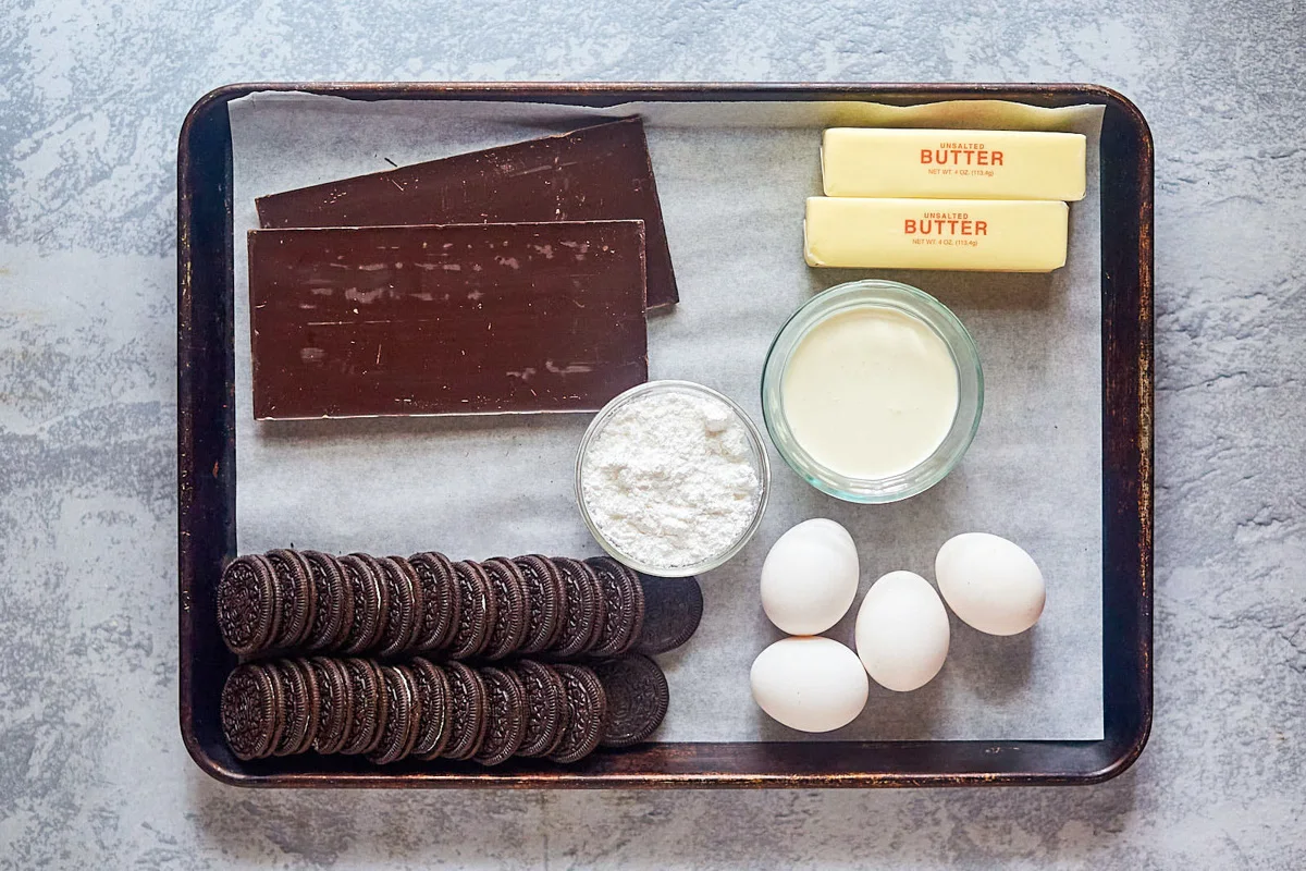 Top down view of the ingredients needed to make a chocolate french silk pie including Oreos, butter, eggs, cream, chocolate, and whipping cream.