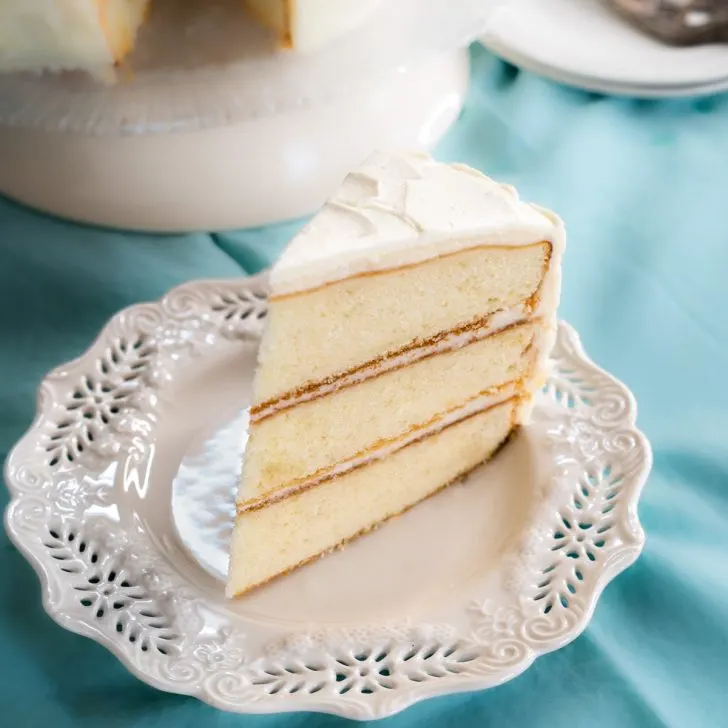 Sideview of a slice of homemade layer cake with white frosting. Hostess At Heart