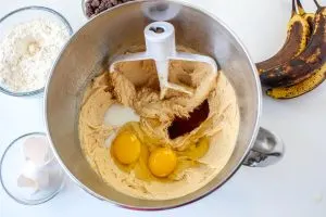 Eggs, milk and vanilla extract added to a mixing bowl filled with creamed peanut butter, butter, and sugar.