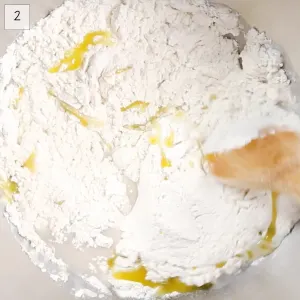 Flour, olive oil stirred into yeast in a glass bowl.