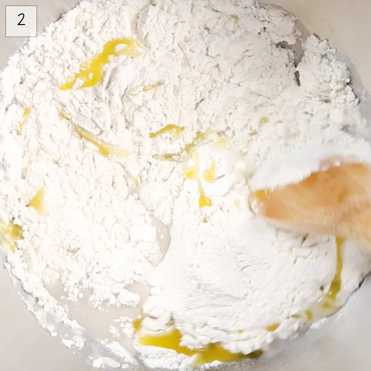 Flour, olive oil stirred into yeast in a glass bowl.