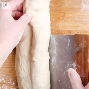 A scraper is folding bread dough onto itself inorder to shape it into a baguette - Hostess At Heart