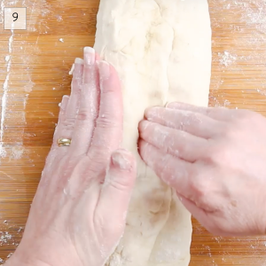 Top-down view of a divot being pressed into bread dough in order to shape it into a baguette - Hostess At Heart