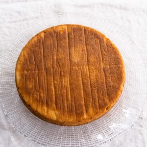 Top down view of a baked round cake on a glass platter. Hostess At Heart