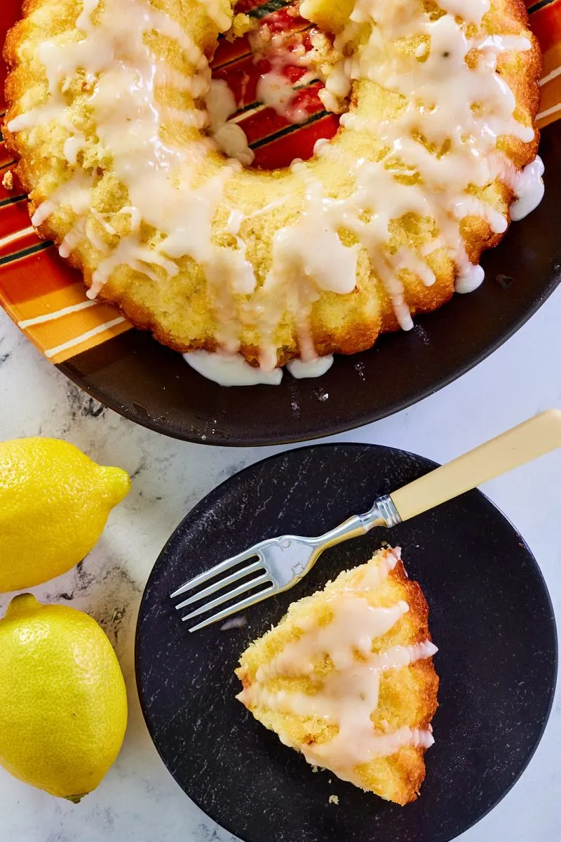 Top-down view of a glazed Sur La Table lemon bundt cake next to a slice - Hostess At Heart