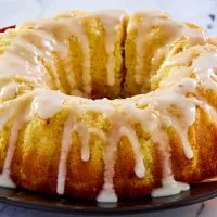 Side view of a lemon olive oil bundt cake drizzled with glaze. - Hostess At Heart